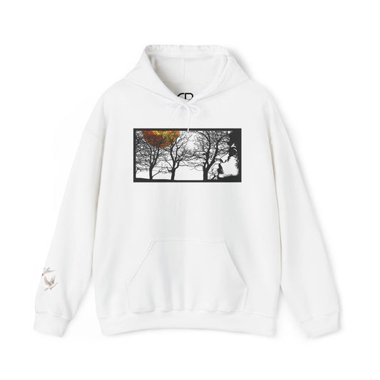 White Through The Wilderness pullover hoodie featuring a black-and-white forest landscape graphic with a glowing autumn leaf on the front and a small bird logo on the left sleeve.